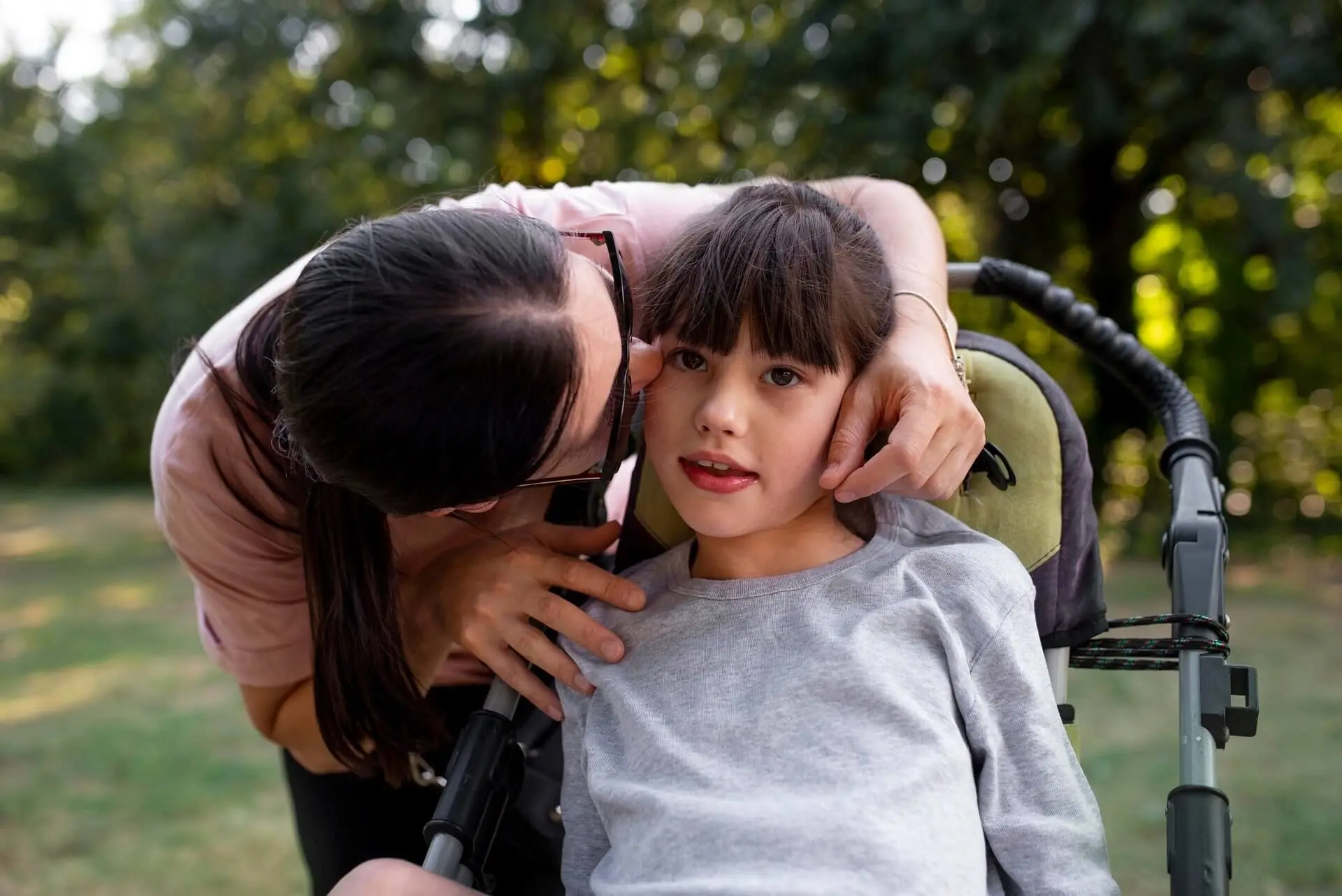 Madre acompaña con cariño a su hija en silla de ruedas, fortaleciendo la comunicación y el vínculo familiar.