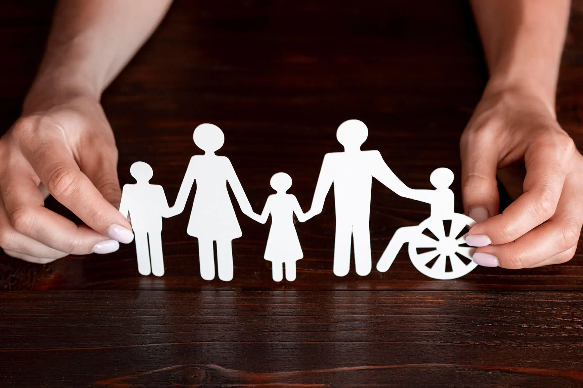 Familia reunida en casa en un entorno inclusivo, conversando con un integrante en silla de ruedas que utiliza un dispositivo de comunicación accesible y aumentativa (CAA).